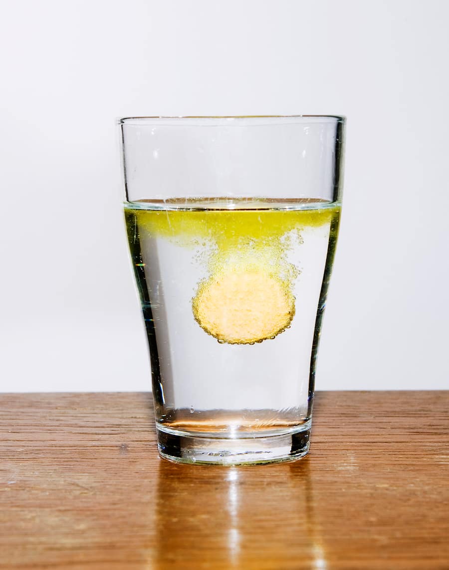 Eine Brausetablette löst sich langsam in einem Wasserglas auf.